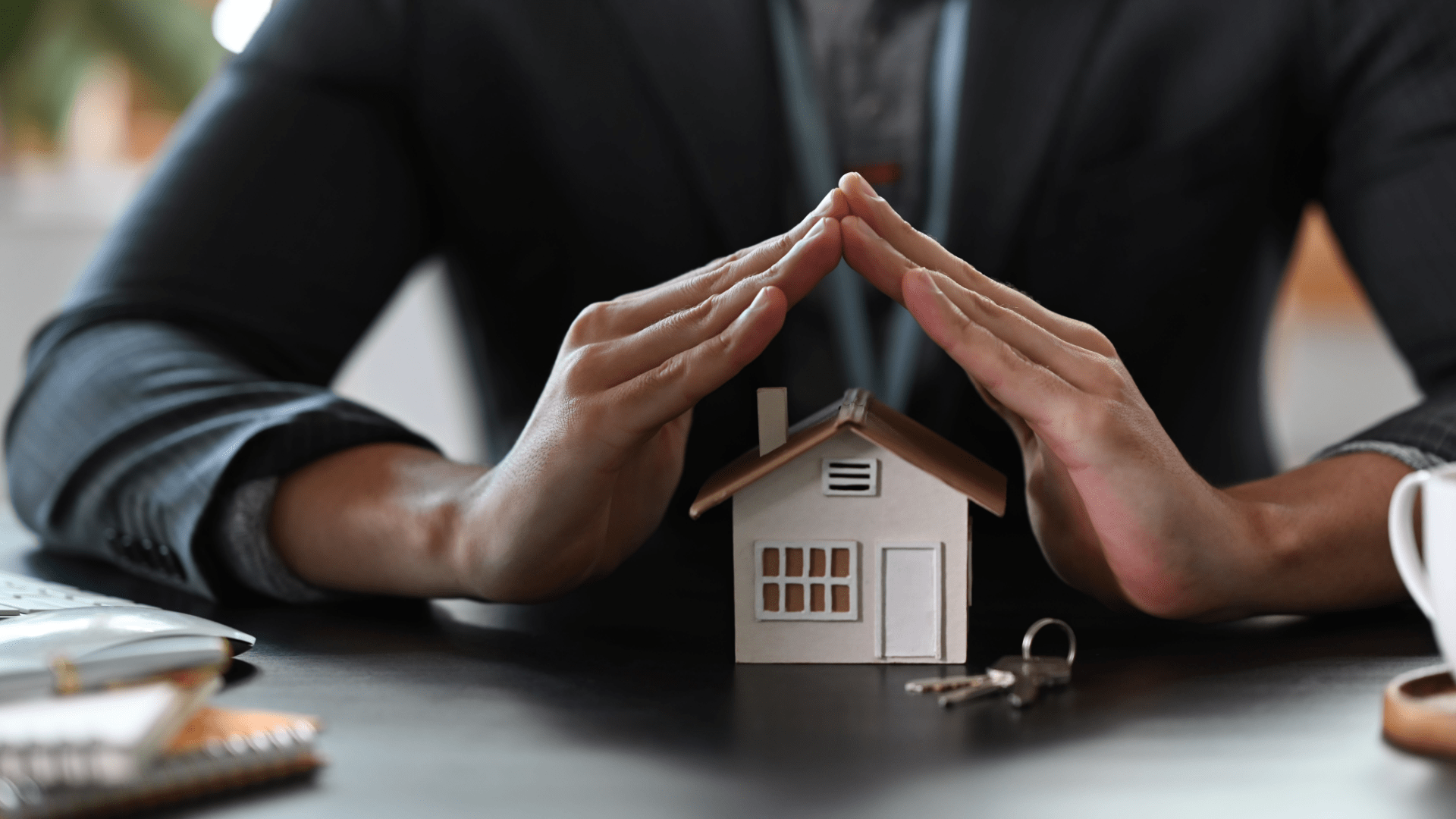 Estate agent hands over house model for protection and care.